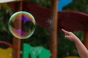 A child's hand pops a balloon. Caught a moment of a bursting balloon. Children play with soap...