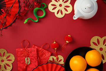 Chinese New Year concept with teapot, oranges, red envelopes, and lanterns on a red background