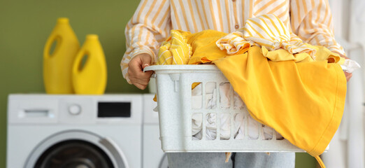 Young woman with laundry basket in room, closeup