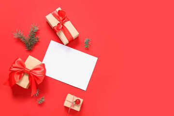 Composition with blank card, Christmas gifts and fir branches on red background