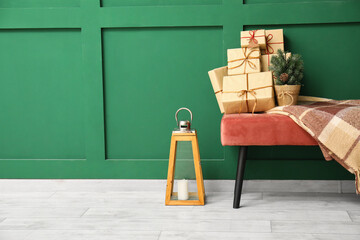 Bench with small Christmas tree and gift boxes near green wall