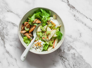 Delicious salad with baked turkey, apple, celery, green salad and Greek yogurt on a light background, top view