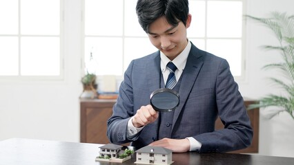 虫眼鏡で家の調査をするビジネスマン