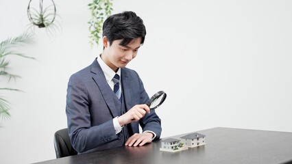 虫眼鏡で家の調査をするビジネスマン