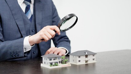 虫眼鏡で家の調査をするビジネスマン