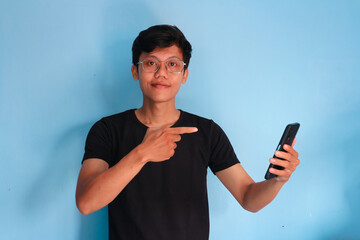 Young Asian man holding his mobile phone with happy expression