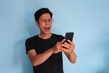 Asian young man looking at his mobile phone with shocked expression