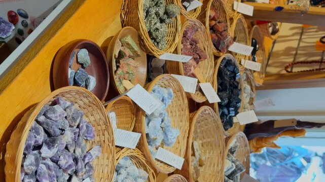 Display with gem stones in baskets in an esoteric shop. Vertical video.
