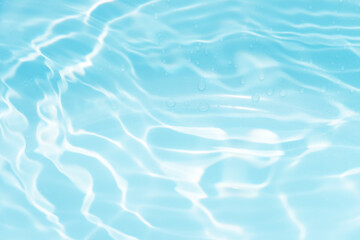 Blue water with ripples on the surface. Defocus blurred transparent blue colored clear calm water surface texture with splashes and bubbles. Water waves with shining pattern texture background.