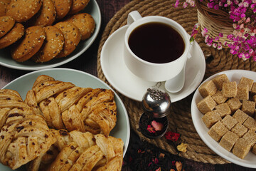 Sweet breakfast. Cup of tea with sweets on a dark table