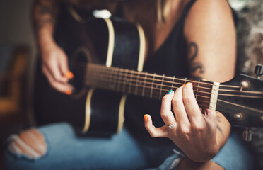 Woman, hands and guitar in living room for music, practice and learning chords on sofa. Musician, string instrument and strumming in home with talent, pitch development and rehearsal for performance