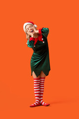 Happy young woman dressed as elf on orange background