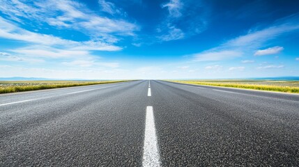 Naklejka premium A straight road stretches into the horizon under a clear blue sky, symbolizing freedom and travel.