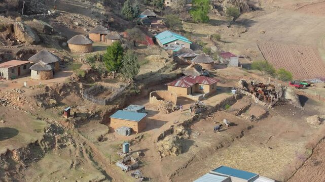 Aerial view of general activity in Basotho rural village. Houses and livestock at foot of hill