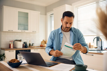 Mid adult man checking mail while working on a computer at home.