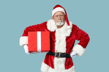 Angry Santa Claus in glasses with gift box on blue background
