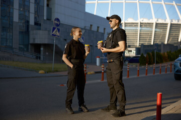 Cheerful patrol officers talking together drinking coffee having work break