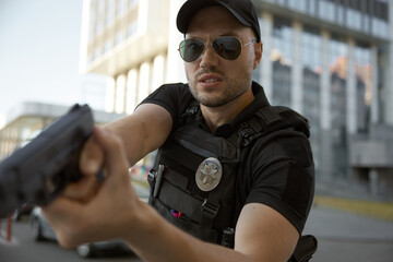 Portrait of man patrol police officer aiming with handgun at city street