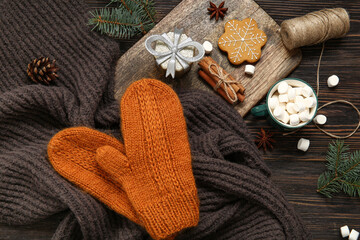 Composition with warm mittens, cup of cocoa drink and Christmas decorations on wooden background,...