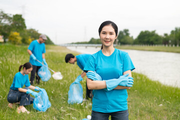 A group of happy volunteers cleaned up the riverside by collecting garbage into garbage bags and separating plastic waste from water bottles. Help keep nature clean. Reduce environmental pollution