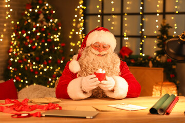 Santa Claus drinking hot chocolate with marshmallows at home on Christmas eve