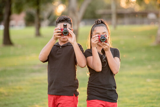 Brother and sister using their cameras to take a pictures