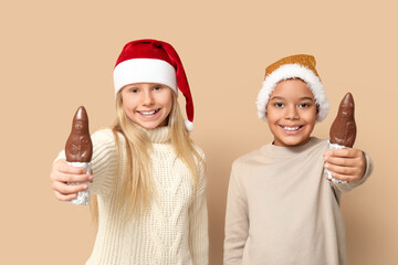 Cute little children with chocolate Santa Claus on brown background