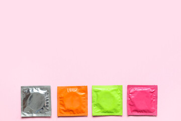 Set of different condoms on pink background