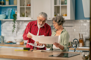 in bright kitchen an elderly neat cute couple at the table count their expenses monthly payment summing up the results of the year utilities counting monthly survival