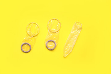 Male and female condoms on yellow background