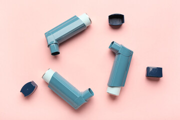 Inhalers and lids on pink background, closeup