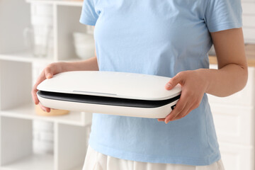 Young woman with vacuum sealer machine for food in kitchen