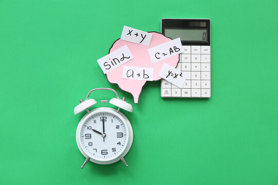 Paper brains with math formulas and equations, with calculator and alarm clock on green background