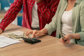 close up in bright kitchen an elderly cute couple at the table count their expenses monthly payment summing up the results of the year utilities count monthly survival count money