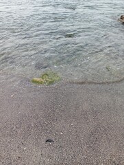 Portrait of waves, sand and small rocks on the beach
