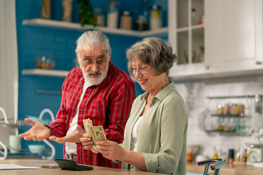 in bright kitchen an elderly cute couple at the table count their expenses monthly payment utility bills monthly survival count money misunderstanding