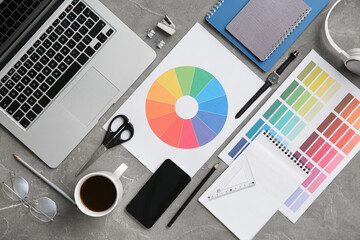 Workplace of graphic designer with laptop, pencils and color charts on grey grunge table