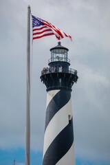 Tourists on top of the The Cape Hatteras Lighthouse and american flag, Buxton, North Carolina,...