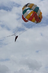 Parasailing Against Clear Blue Sky and Clouds at Bali Beach – Thrilling Aerial Adventure Over Stunning Coastal Scenery in Indonesia’s Tropical Paradise