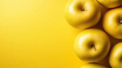 Glossy yellow apples cluster together on a minimal yellow surface, embodying wholesomeness and purity. Their placement creates a simple yet effective visual composition.