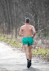 A man is running in the woods wearing green shorts