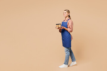 Full body young woman barista bartender barman wear blue apron work in coffee shop hold takeaway...