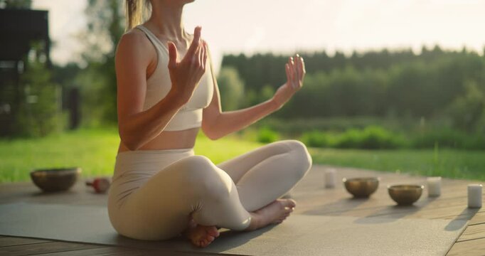 Anonymous Female Sits Cross-Legged, Meditating in a Nature Retreat, Blending with Peaceful Forest Surroundings. Incense Gives Soothing Aromas, while the Harmonious Tones of Singing Bowls Resonate
