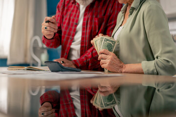 close-up in bright kitchen hands with American bills calculator payment receipts calculator hard...