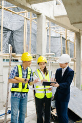 Contractor and architect looking at plan, tablet, laptop and talking about working on big project.