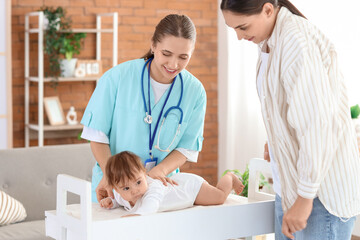 Fototapeta premium Female pediatrician with little baby lying on changing table and mother at home