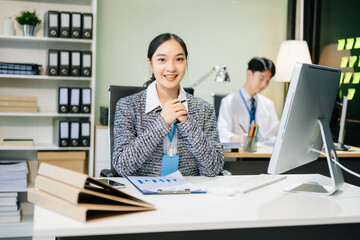 Asian female office worker business suits smiling at camera with working notepad, tablet and laptop documents .