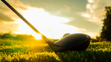 Golf clubs and golf balls on a green lawn in a beautiful golf course with morning sunshine.