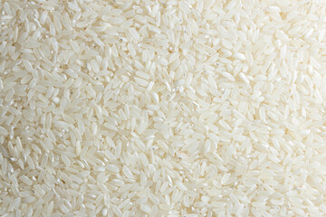 Dry Uncooked White Rice Background - Top View, Flat Lay. Scattered Raw Long Grain Rice. Asian Cuisine and Culture. Healthy Eating Ingredients. Diet Food