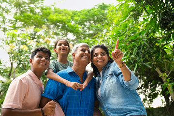 Indian Asian family of four, parents in their forties with two children, in outdoor pointing happily